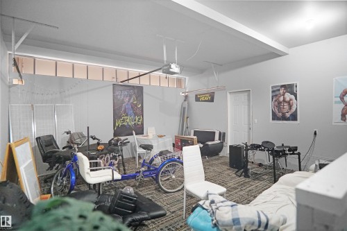 Interior space featuring light gray walls, a textured carpeted floor, and a white ceiling with an exposed garage door track - 4816 155 Ave, Edmonton, AB 