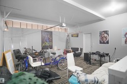 Interior space featuring light gray walls, a textured carpeted floor, and a white ceiling with an exposed garage door track - 
