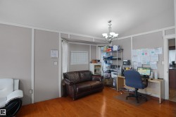 Room featuring wood-finish flooring, light grey walls with white trim paneling, and a vaulted ceiling with a chandelier - 