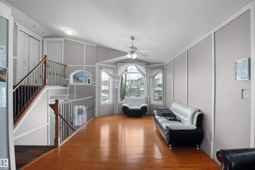 Living area featuring wood-finish flooring, a multi-pane bay window, and a ceiling fan - 4816 155 Ave, Edmonton, AB 