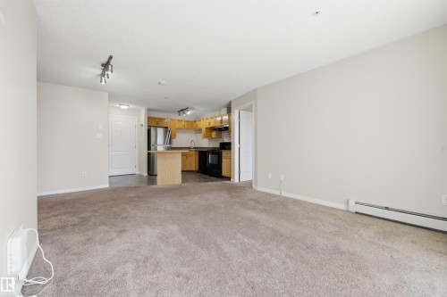 Open concept living area featuring a neutral carpet and light-toned walls - 201 3425 19 Street Nw, Edmonton, AB 