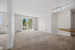 Living area featuring neutral-tone carpeting, light-colored walls, and a sliding glass door opening to a balcony - 