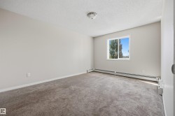 Neutral-toned room featuring a single window, baseboard heating, and textured carpeting - 