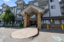 North Building entrance featuring a decorative stone facade, an arched window, and a covered entry - 201 3425 19 Street Nw, Edmonton, AB 