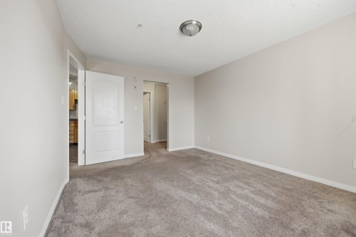 Carpeted room with light neutral wall paint and white baseboards - 201 3425 19 Street Nw, Edmonton, AB 