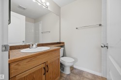 Ensuite bathroom featuring a wood-finish vanity with a built-in sink, a laminate countertop, and a large wall-mounted mirror. The tub and shower are behind the door. - 