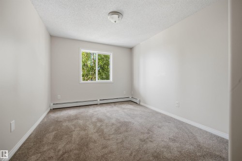 Carpeted interior room featuring light-toned walls, white trim. - 201 3425 19 Street Nw, Edmonton, AB 