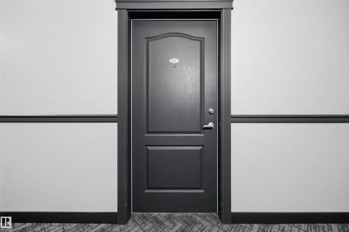 Paneled door with dark trim, featuring a door handle and deadbolt - 201 3425 19 Street Nw, Edmonton, AB 