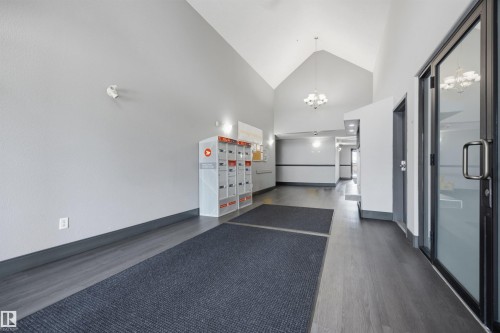 North enternace common area featuring vaulted ceilings, wood-finish flooring, recessed lighting, and chandelier fixtures - 201 3425 19 Street Nw, Edmonton, AB 