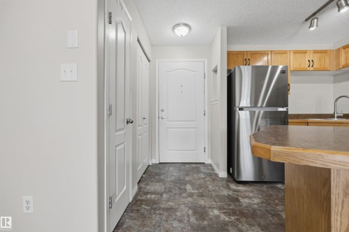 Entryway with a front closet with bi-fold doors and the kitchen pantry. - 201 3425 19 Street Nw, Edmonton, AB 