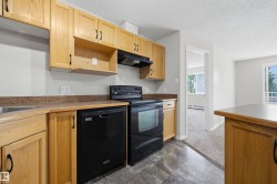 Kitchen featuring wood-finish cabinetry, dark countertops, black range, and black dishwasher - 