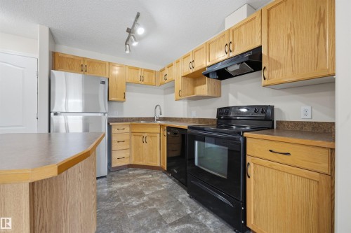 Kitchen featuring light wood cabinetry and dark countertops - 201 3425 19 Street Nw, Edmonton, AB 
