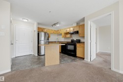 Kitchen area featuring wood-finish cabinetry, dark countertops, a stainless steel refrigerator, and a black range - 