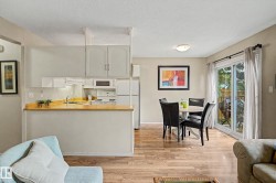 Kitchen with light cabinetry and wood-finish countertops, featuring a built-in microwave and white appliances - 