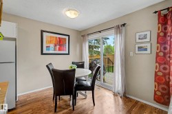 Kitchen dining area featuring wood-finish flooring, light neutral wall paint, and a sliding glass door providing access to an exterior deck - 