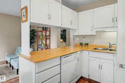 Kitchen featuring white cabinetry, wood-finish countertops, stainless steel double basin sink, and an integrated dishwasher - 19 Pineview Drive, St. Albert, AB 