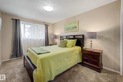 Carpeted bedroom featuring a large window with sheer and blackout drapes, a flush-mount ceiling light, and neutral wall tones - 