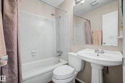Bathroom featuring a pedestal sink, wall-mounted mirror, medicine cabinet, toilet, and a tub-shower combination with white tile surround - 
