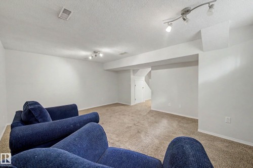 Carpeted living space featuring recessed lighting, track lighting, and white walls with base molding - 19 Pineview Drive, St. Albert, AB 