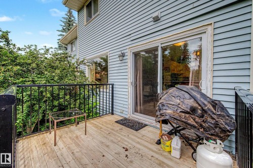 Wood-finish deck with black metal railings, light blue horizontal siding, and a sliding glass door - 19 Pineview Drive, St. Albert, AB 