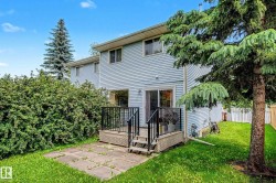 Rear exterior featuring light blue siding, a wooden deck with black railings, and a concrete patio - 