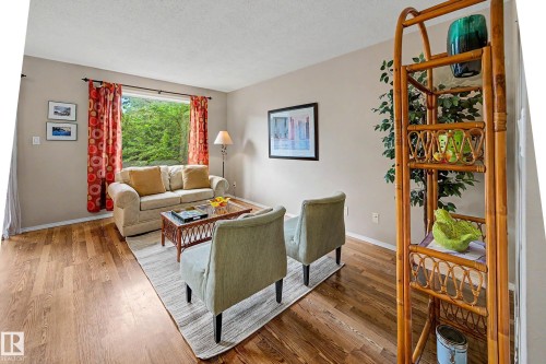 Spacious living area featuring wood-finish flooring, neutral wall tones, and a large picture window - 19 Pineview Drive, St. Albert, AB 