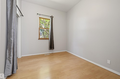 Bright interior space featuring wood-finish flooring, light grey painted walls, white baseboards, and a double-hung window with wood trim - 11450 71 Street Nw, Edmonton, AB 