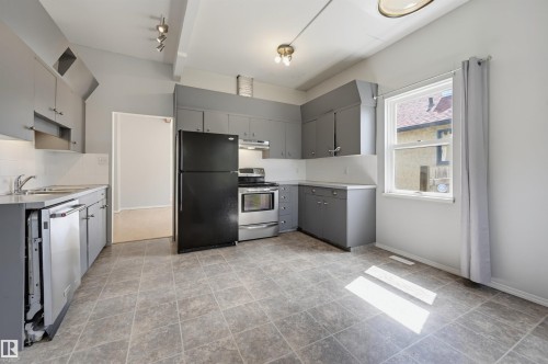 Kitchen featuring grey cabinetry, stainless steel appliances, a white tile backsplash, and durable tile flooring - 11450 71 Street Nw, Edmonton, AB 