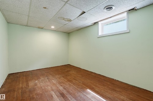 Spacious room featuring wood-finish flooring and light green walls - 11450 71 Street Nw, Edmonton, AB 