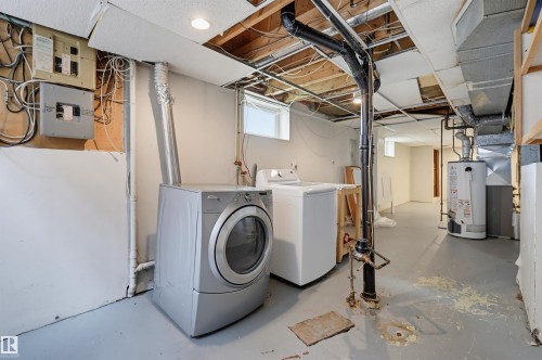Utility area featuring laundry appliances, exposed ceiling joists, and a water heater - 11450 71 Street Nw, Edmonton, AB 