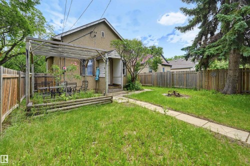 Spacious backyard featuring a pergola-covered patio, mature trees, wood fencing, and a concrete pathway - 11450 71 Street Nw, Edmonton, AB 