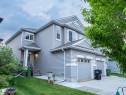 Multi-story residence featuring light gray siding with white trim, an attached two-car garage with panel detailing, and a covered entry porch - 5407 14 Avenue, Edmonton, AB 