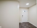 Entryway featuring a white paneled door with transom windows, dark square floor tiles, and recessed ceiling lighting - 5407 14 Avenue, Edmonton, AB 