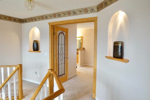 Carpeted hallway featuring a decorative wallpaper border and a glass-paneled interior door - 8504 160A Avenue, Edmonton, AB 