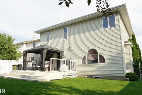 Spacious backyard featuring a multi-level deck, white railing, and a manicured lawn - 8504 160A Avenue, Edmonton, AB 