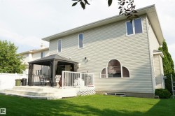 Spacious backyard featuring a multi-level deck, white railing, and a manicured lawn - 