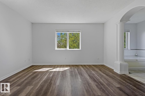 Spacious interior room with wood-finish flooring and a large window - 6 1237 Carter Crest Road, Edmonton, AB 