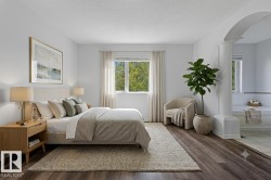 Spacious sleeping area featuring wood-finish flooring and an arched entryway to a tiled bathing area with a built-in tub - 