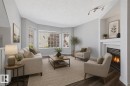 Living space featuring wood-finish flooring, a bay window, and a built-in fireplace with a white mantel and hearth - 6 1237 Carter Crest Road, Edmonton, AB 