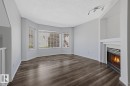 Living space featuring a corner fireplace with a white mantel, bay windows, and dark wood-finish flooring - 6 1237 Carter Crest Road, Edmonton, AB 
