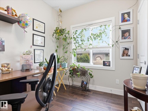 Room featuring a built-in wood-finish desk with integrated cabinetry, wood-finish flooring, a window with blinds, and white trim - 12820 68 Street, Edmonton, AB - Indoor Photo Showing Office