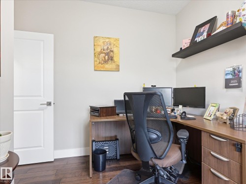 Room featuring wood-finish flooring, light-toned walls, and a modern white door with a brushed nickel handle - 12820 68 Street, Edmonton, AB - Indoor Photo Showing Office