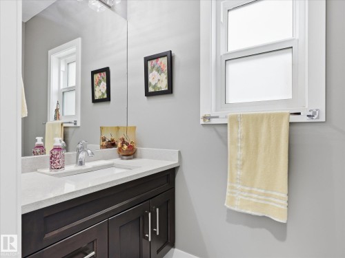Dark wood-finish vanity with a light-toned countertop, undermount sink, and chrome faucet - 12820 68 Street, Edmonton, AB - Indoor Photo Showing Bathroom