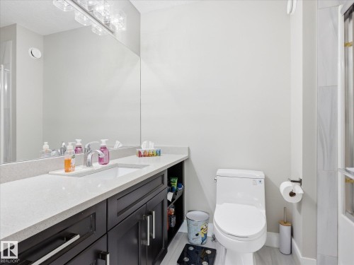 Bathroom featuring a dark wood-finish vanity with a light countertop, an undermount sink, and a large mirror - 12820 68 Street, Edmonton, AB - Indoor Photo Showing Bathroom