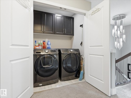 Dedicated laundry area featuring dark cabinetry, side-by-side appliances, and light tile flooring - 12820 68 Street, Edmonton, AB - Indoor Photo Showing Laundry Room