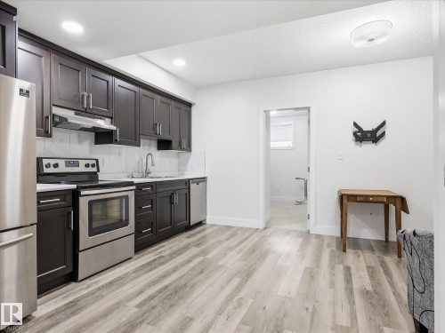 Kitchen featuring dark wood-finish cabinetry, stainless steel appliances, white countertops, and a white subway tile backsplash - 12820 68 Street, Edmonton, AB - Indoor Photo Showing Kitchen