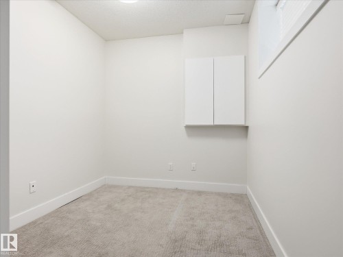 Neutral-toned room featuring a window, built-in wall cabinet, recessed lighting, baseboards, and carpeted flooring - 12820 68 Street, Edmonton, AB - Indoor Photo Showing Other Room