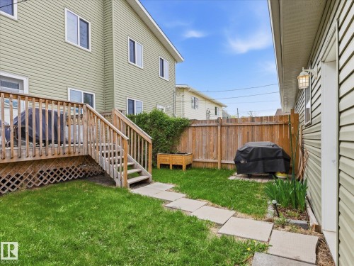 Spacious backyard featuring a wooden deck with lattice skirting, stone pathway, and a privacy fence - 12820 68 Street, Edmonton, AB - Outdoor With Exterior