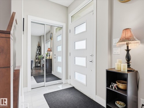 Foyer featuring a contemporary front door with privacy glass inserts, white tile flooring, and a mirrored closet with sliding doors - 12820 68 Street, Edmonton, AB - Indoor Photo Showing Other Room