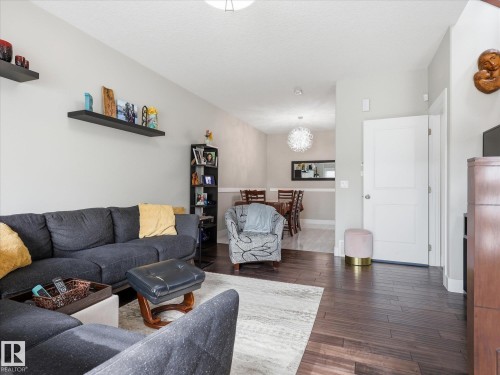 Open-concept living area featuring rich wood-finish flooring, light grey wall tones, and recessed lighting - 12820 68 Street, Edmonton, AB - Indoor Photo Showing Living Room